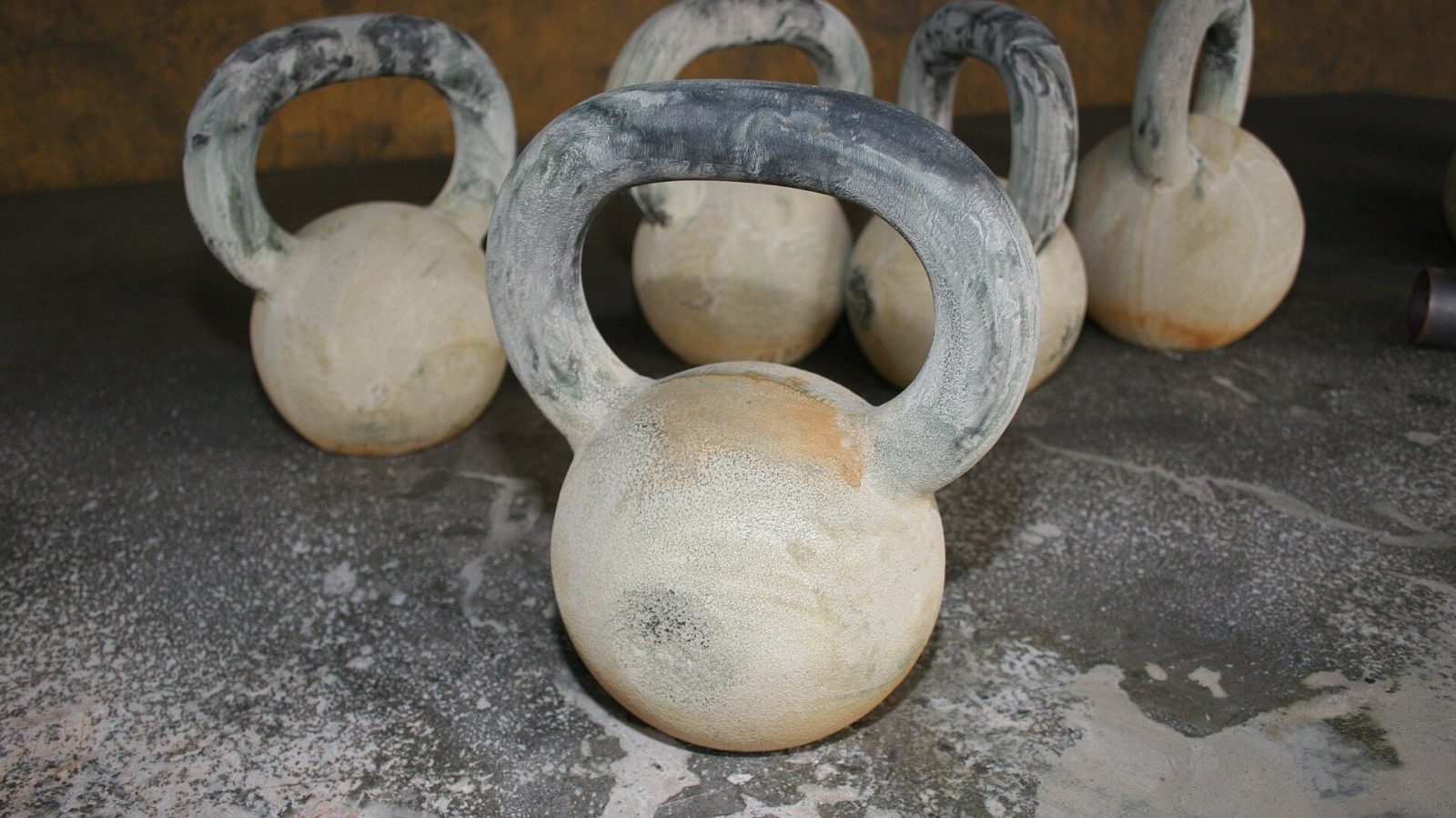 Kettlebells coated in white dust on a concrete floor